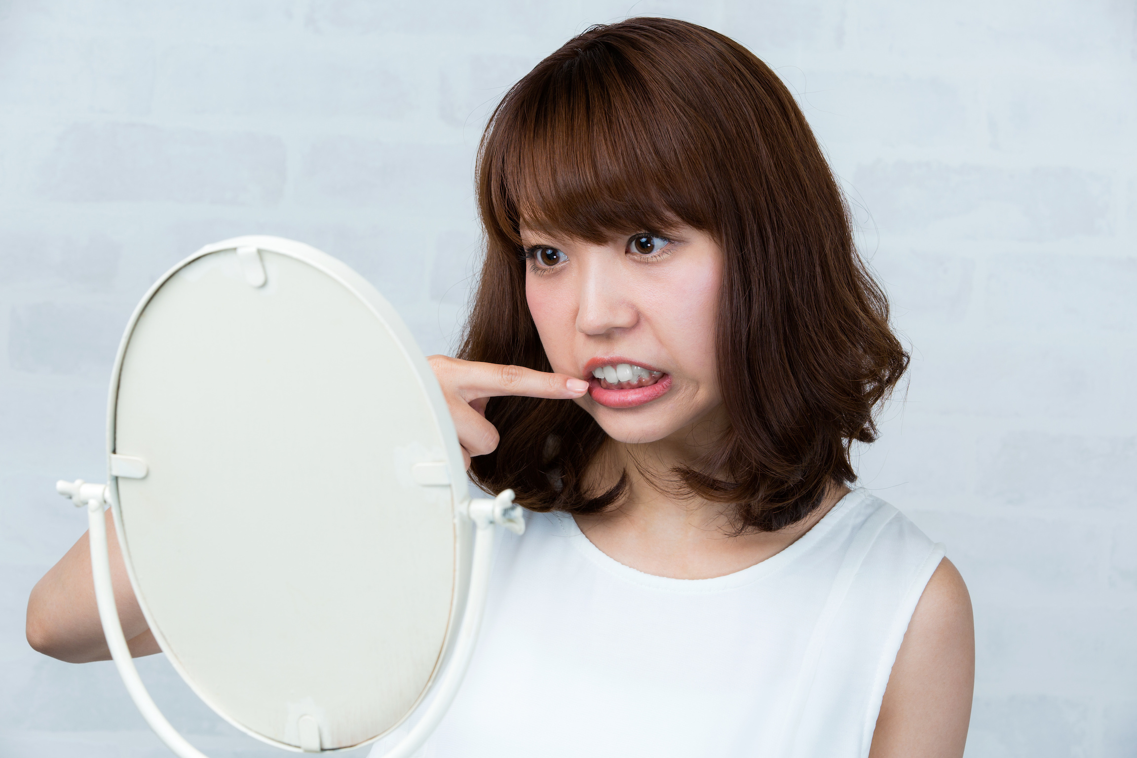 鏡で歯を見る女性